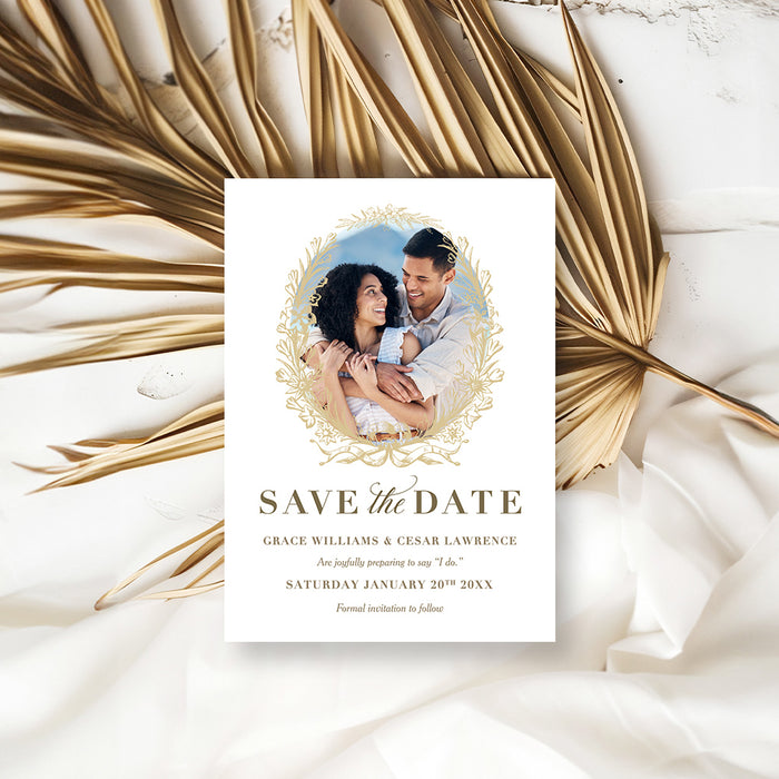 Wedding save the date card with a couple photo framed by a gold floral wreath, personalized names and wedding date-front