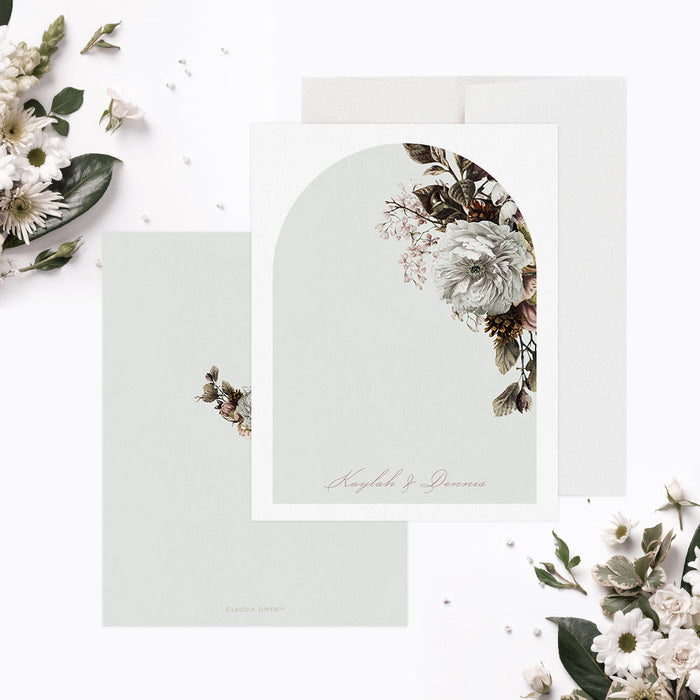 Front and back of personalized note cards with white flowers and greenery around an arch design with personalized names and a pale green back with a white floral illustration.