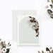 Personalized note card with white flowers and greenery around an arch design with personalized names, shown with a white envelope.