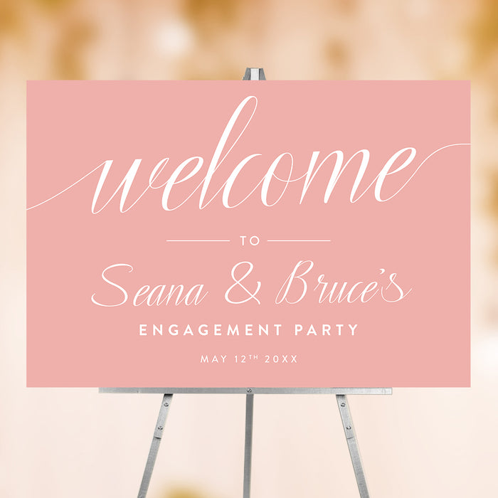 Romantic pink engagement party welcome sign with elegant script lettering displayed on an easel for a wedding celebration