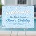 Slip and slide welcome sign with water drop design for kids pool party birthday displayed on easel for summer splash themed celebration