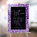 Purple bachelorette party welcome sign featuring a stiletto heels pattern, displayed on an easel.