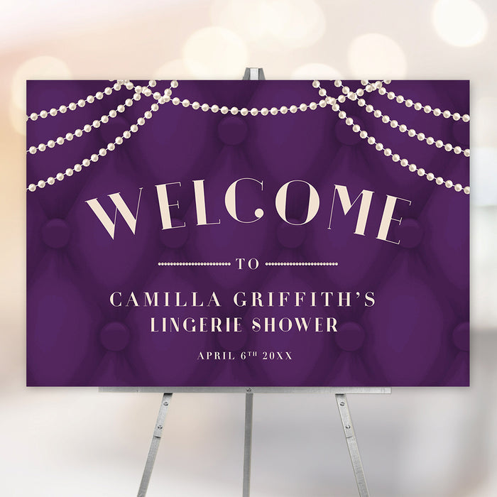 Lingerie shower welcome sign featuring a tufted deep purple background with cascading pearl accents