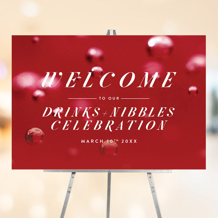 red cocktail party welcome sign with Drinks and Nibbles wording, bubbly drink-inspired background, and custom celebration details