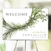 Rehearsal dinner welcome sign featuring a delicate arrangement of green botanical foliage, perfect for wedding entrance decor and photo backdrop displays