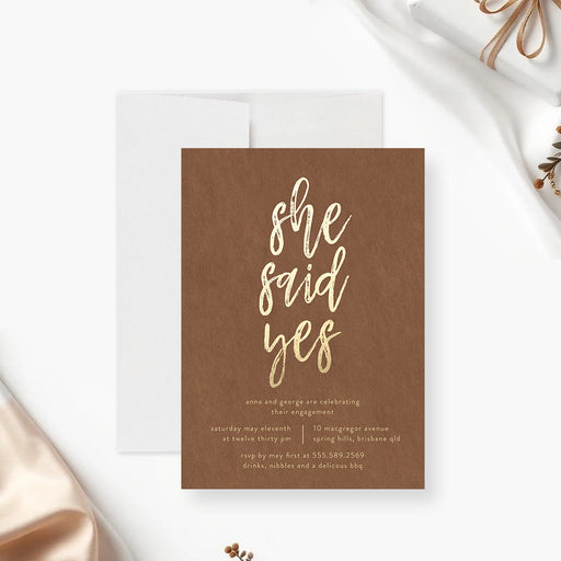 She said yes to the engagement invitation card featuring a brown background and gold lettering for a romantic engagement party-front