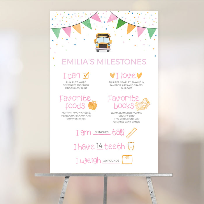 Personalized school bus first birthday milestone sign featuring colorful bunting, baby milestones, favorite foods, favorite books, height, weight, and birthday party decoration displayed on an easel.