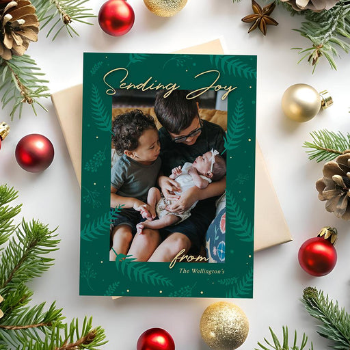 Sending joy holiday photo card featuring green leaf border and family photo