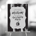 Black Halloween welcome sign featuring an elegant spooky design with witch cauldron illustration for a stylish party entrance display