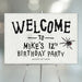 Spooky spider web birthday party welcome sign with black lettering and spider illustration