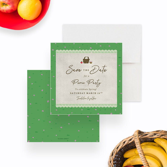 spring picnic party save the date card with picnic basket illustration, lace border, green grass pattern, and tiny pink flowers-front-back