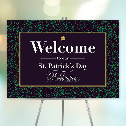 A festive black and gold St. Patrick's Day welcome sign with a golden shamrock, displayed on a stand.