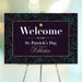 A festive black and gold St. Patrick's Day welcome sign with a golden shamrock, displayed on a stand.