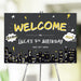 Superhero-themed welcome sign with comic graphics, city skyline, and bold lettering for a child’s birthday party entrance
