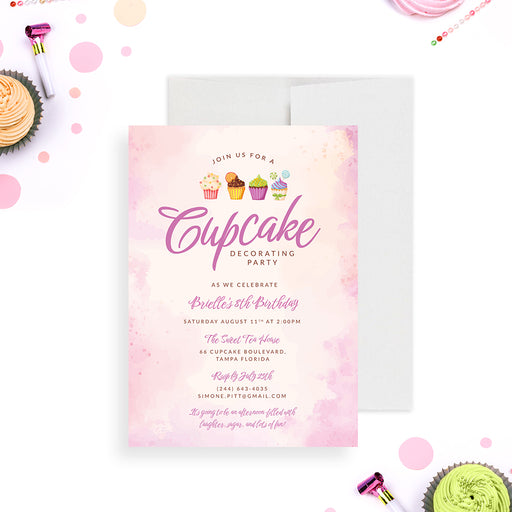 A blush pink invitation card with cupcake illustrations and details for a cupcake decorating party, displayed with cupcakes and party decorations in the background.