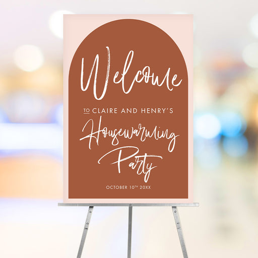 housewarming welcome sign with a terracotta arch on a blush pink background and elegant script lettering