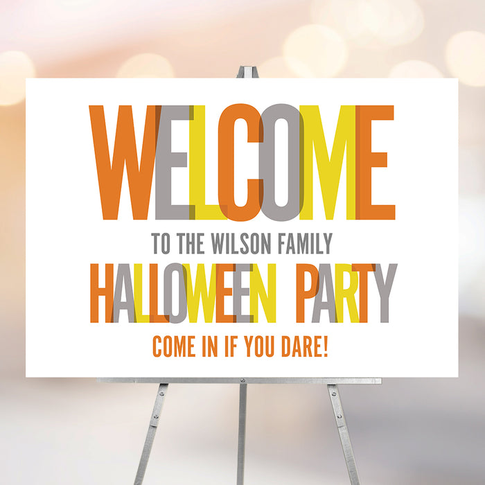 Colorful Halloween party welcome sign with bold orange, yellow, and gray lettering displayed on an easel.