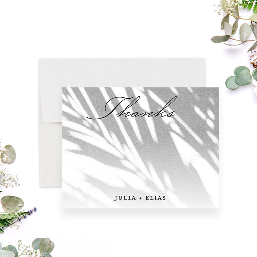 tropical wedding thank you card with soft palm shadow design and elegant script lettering for a beach or garden wedding-front
