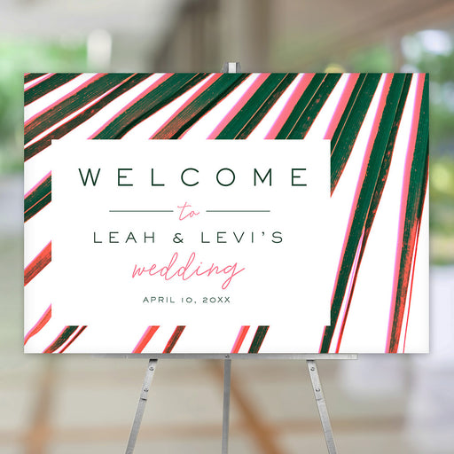 Tropical welcome sign featuring bright pink and green palm fronds, suitable for wedding ceremony entrances, reception displays, or event décor.