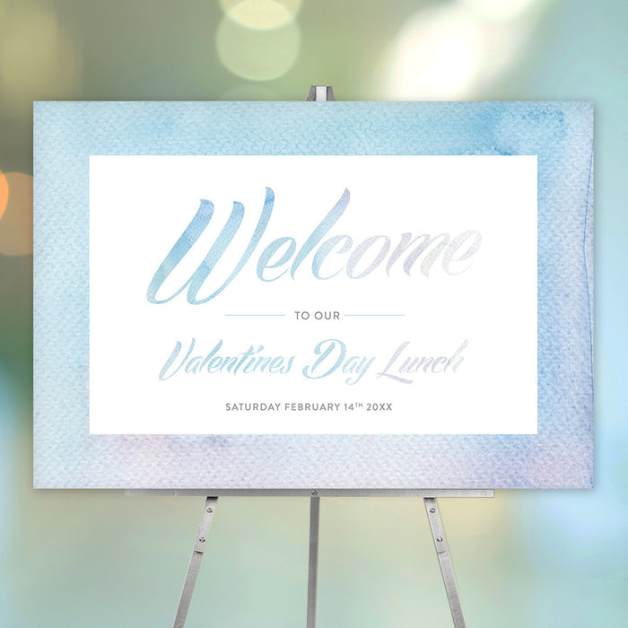 Valentine's Day welcome sign with soft blue watercolor border, elegant script lettering, and personalized lunch details displayed on an easel