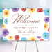colorful watercolor floral garden party welcome sign with elegant lettering, personalized family text, and easel display