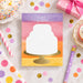 Kids birthday thank you card featuring a watercolor cake illustration on a gold stand with colorful layered background and personalized name-front