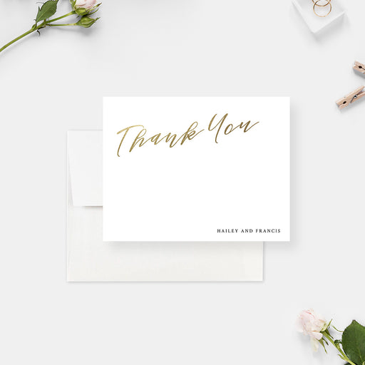 White wedding thank you cards with printed gold script lettering and personalized names on the front and a monogram on the reverse.