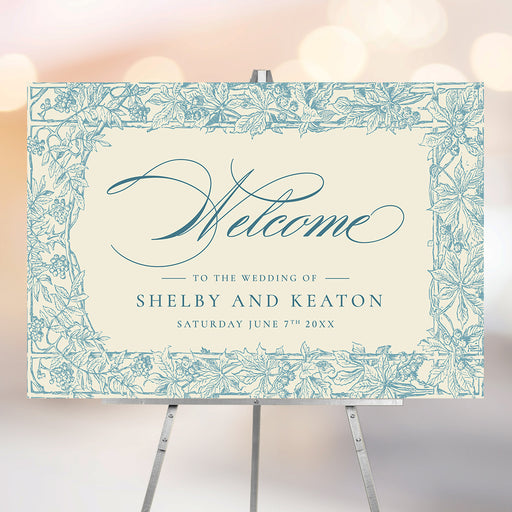 Blue botanical wedding welcome sign with vintage floral border and ivory background displayed on easel