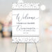 Elegant quinceanera welcome sign with diamond border design displayed on an easel for a Sweet 15 celebration.