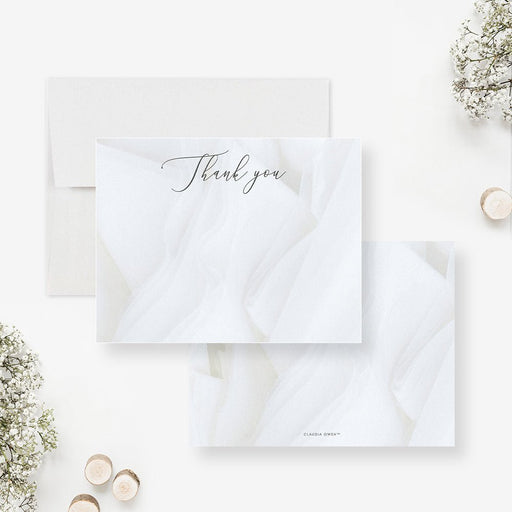 White thank you cards with dark script lettering over a printed folded fabric design on the front and a matching white fabric print reverse.