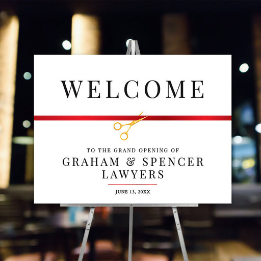 Grand opening welcome sign with gold colored scissors cutting a red ribbon on a white background.