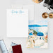 Santorini note cards with a blue script name on the white front and a watercolor scene of blue domes, white buildings and sea on the back.