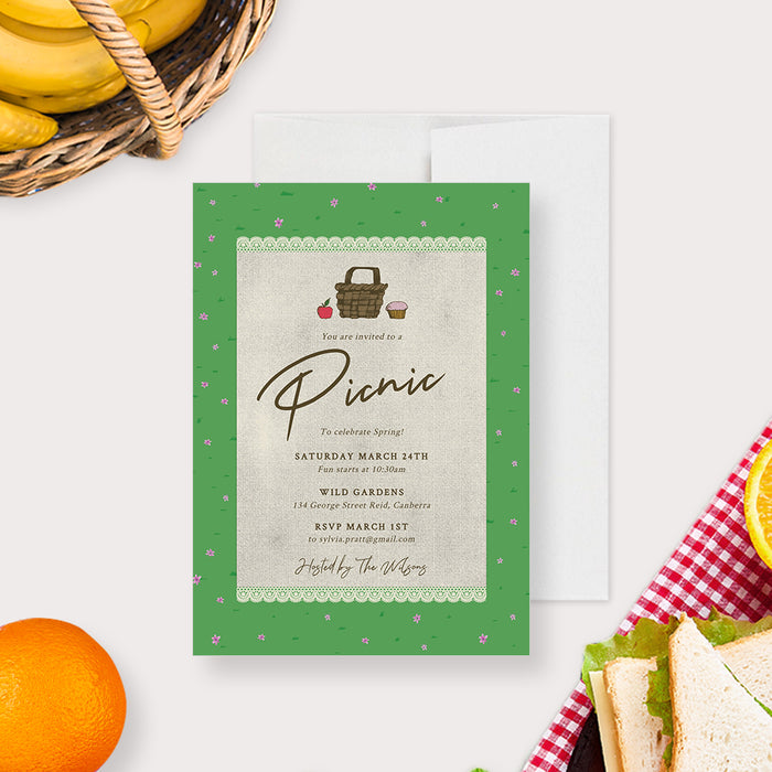 editable picnic party invitation template with picnic basket, lace blanket detail, green garden border, tiny pink flowers, and spring picnic theme